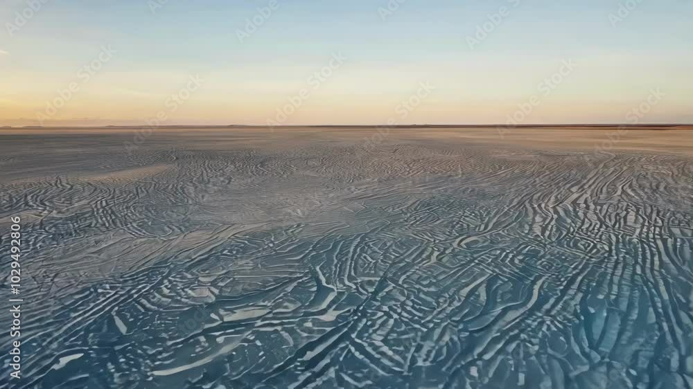 Poster The receding tide reveals beautiful sand patterns with a golden glow at the beach, creating a tranquil scene