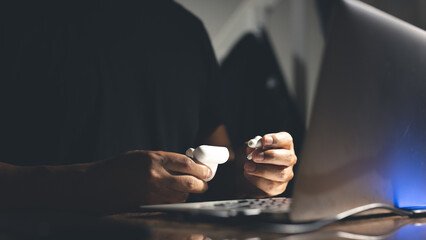 young entrepreneur working using wireless headphones on his phone to listen to music in the office
