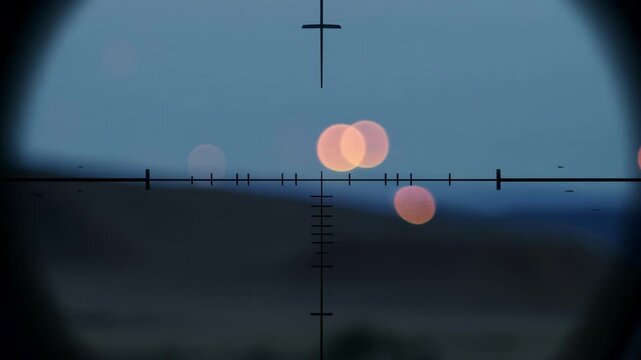 Sniper scope is aiming at a city in the distance, with the lights blurred by the optics and a body of water in the foreground