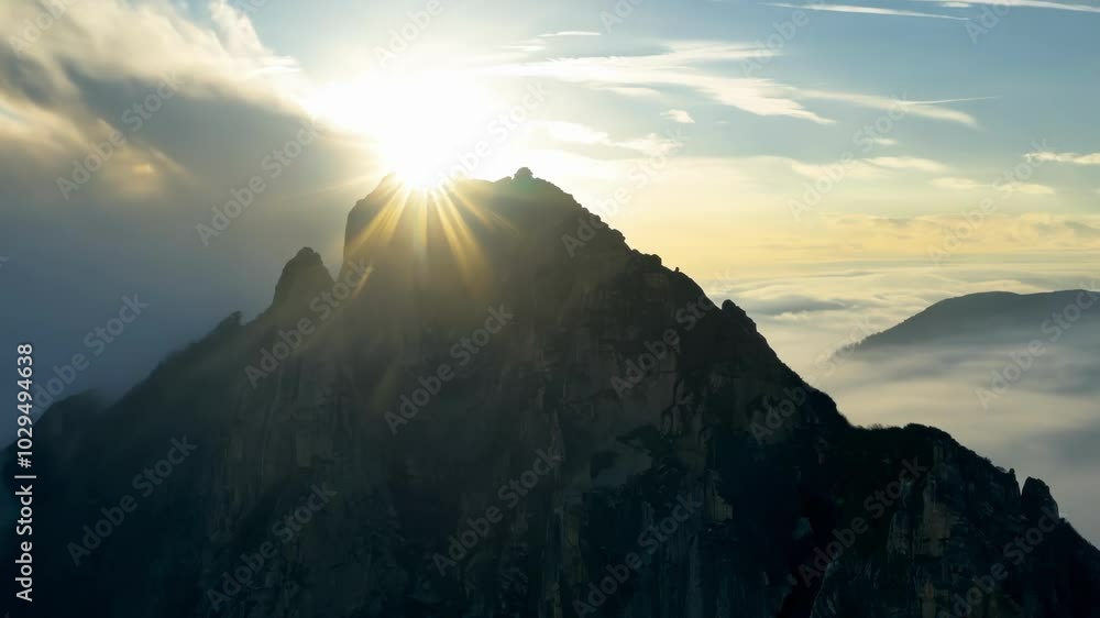Poster the sun shines through dramatic clouds over a rocky mountain peak, creating a beautiful contrast of 