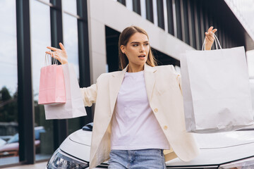 Confident Woman Holding Shopping Bags Outside Modern Store