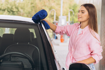 Young Woman Cleaning Car with Blue Cloth at Car Wash