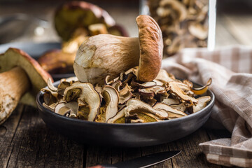 Dried porcini mushrooms. Sliced boletus on plate on wooden table.