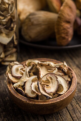 Dried porcini mushrooms. Sliced boletus in wooden bowl on wooden table.
