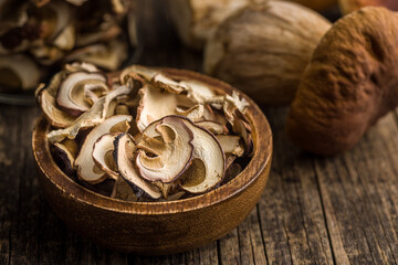 Dried porcini mushrooms. Sliced boletus in wooden bowl on wooden table.