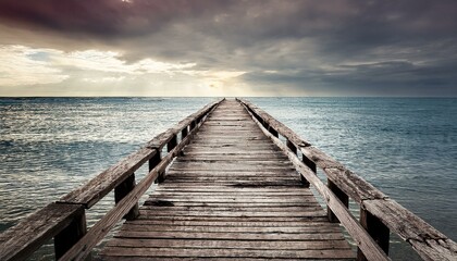 Obraz premium Aged wooden pier with rough, splintered edges, leading into an overcast sky and peaceful, op