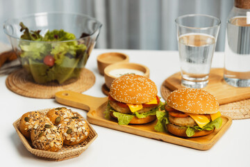 Tasty food in double meat hamburger, salad, wholegrain bun on meal cooked by homemade serving on white table. Preparing special dish to lay out photo shooting menu list's restaurant or cafe. Infobahn.