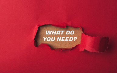 A red paper with a hole in it and the words What do you need written on it