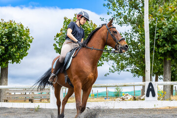 A woman is riding a brown horse in a field