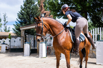 Female rider mounting a horse at the stable