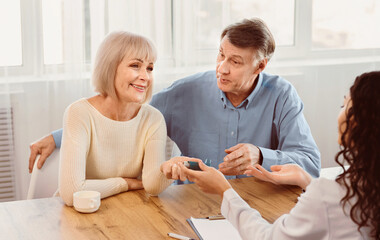 Lung Disease. Female physician giving asthma inhaler to smiling elderly woman, senior couple at doctors office, copyspace