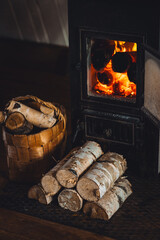 Wicker basket with wood near cozy fireplace in a countryside cottage. Winter vibes, home atmosphere