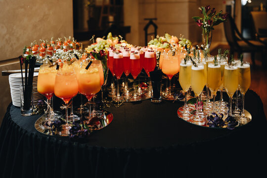 Beautiful line of different colored alcohol cocktails with mint oin the restaurant, tequila, martini, vodka, and others on decorated catering bouquet table on open 