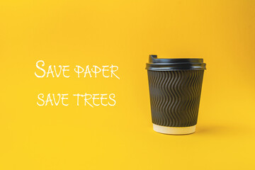 A black coffee cup with a white lid sits on a yellow background