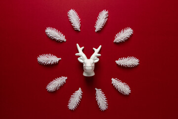 White reindeer with white pine tree branches on red backdrop. Minimal New Year or Christmas...