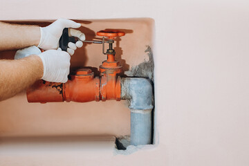 Plumber Wearing Gloves Is Using An Adjustable Wrench To Fix A Water Pipe