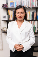 A female psychoanalyst or psychologist in her office with a bookcase behind her