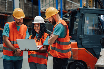 Warehouse workers analyzing data on laptop in a warehouse