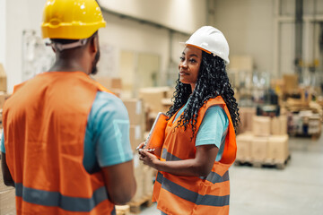 Warehouse workers discussing logistics using digital tablet