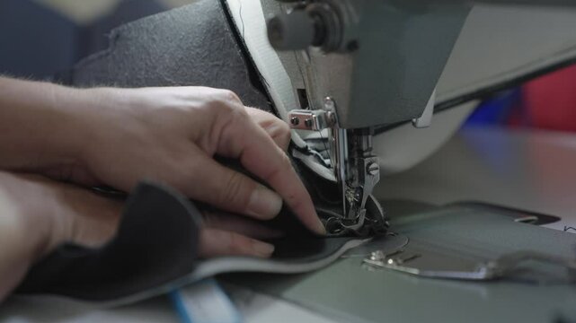 hands seamstress sew product from leather fabric sewing machine. concept female business work home. tailor sews high quality fabric. concept work private leather workshop motion. needle process sewing