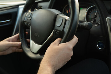 Male hands grip the car's steering wheel, conveying confidence and control over the road. Safe driving requires focus and responsibility, especially at high speeds.