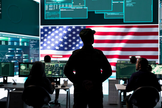 American military personnel ensuring servers protection and classified information, protecting state secrets in high tech agency office. Army soldier supervises hacking activity.