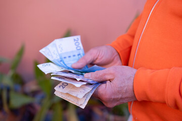 male hands holding money, counting Moroccan dirham bills, rejoices in success, anticipates what to...