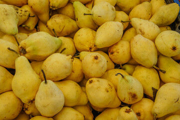 A close-up view of a pile of ripe yellow pears in a market