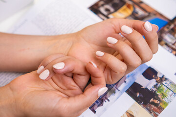 Beautifully manicured hands with gel polish rest on a magazine, highlighting a stylish look