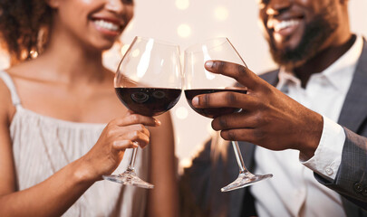 Close up of cheerful african american couple toasting with red wine, celebrating anniversary