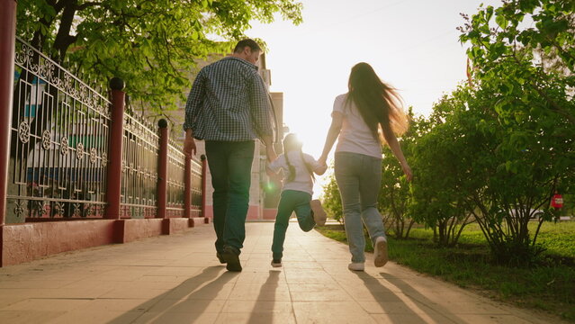 happy family. mother father child run through park sunset. mom dad kid fun running sun. view from back. happy family park. chidhood dream. family walk with kid around city playing. run teamwork