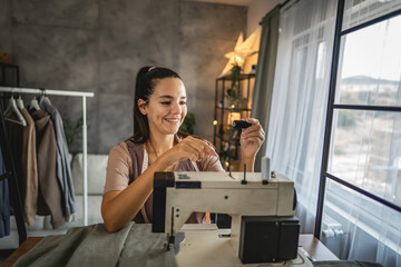 adult woman puts a spool on a sewing machine, preparing it for work.