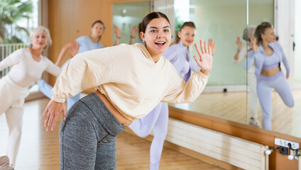 Obraz premium Practiced young woman engaging in fitness dance in dance studio during workout session. Women training dance in hall