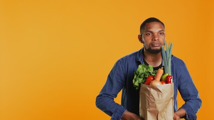 Young adult pretending to lift weight with a paper bag full of bio groceries, mimicking workout...