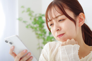 スマホを見て冴えない表情をする女性