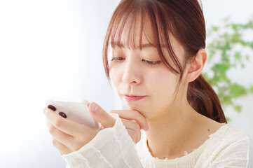 スマホを見て冴えない表情をする女性