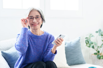 リビングでスマートフォンを使う中高年の女性のポートレート