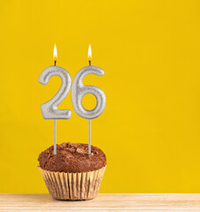 Number 26 birthday candle - Chocolate cupcake on a yellow background.