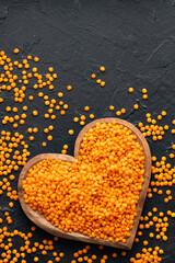 Unshelled red lentil in heart bowl - Lens culinaris.