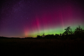 Purple aurora fills the night sky with red and green aurora below