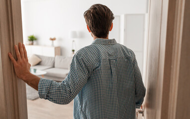 Back rear view of unrecognizable young man walking in his apartment, entering new home, casual guy...