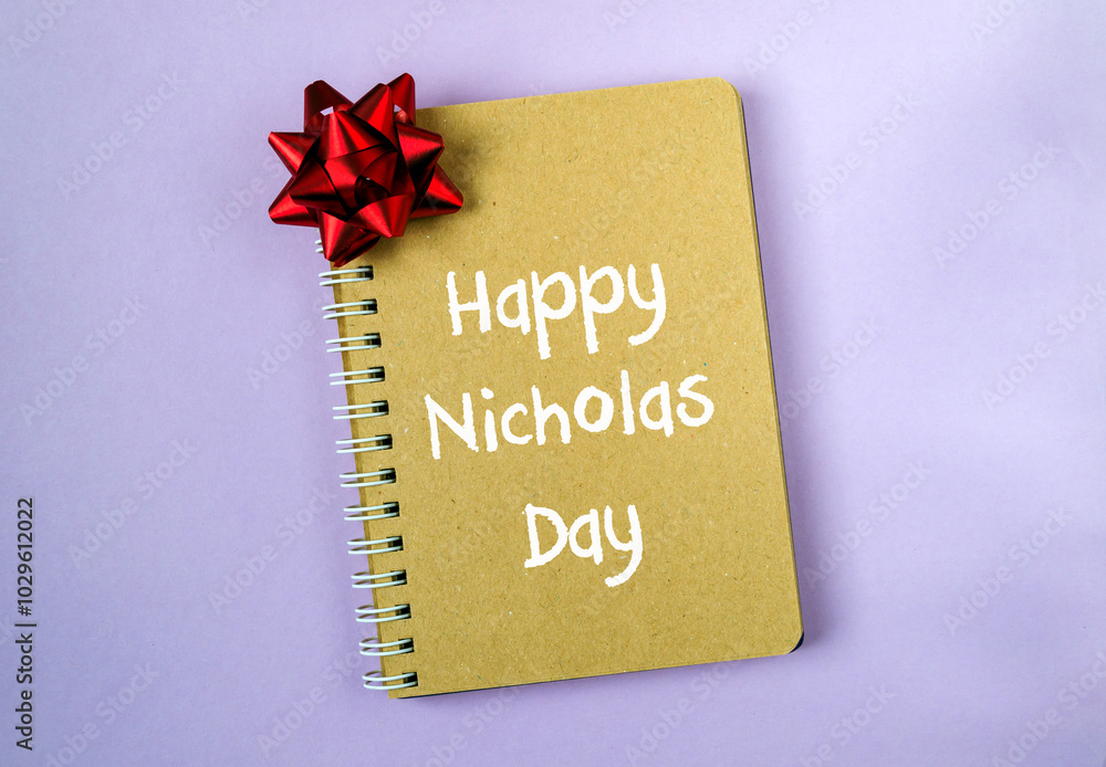 Poster a notebook with a red bow on it with the words happy nicholas day written on it