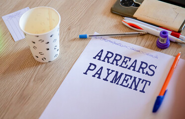 On the table are a pen and a notebook with the inscriptions - Arrears.