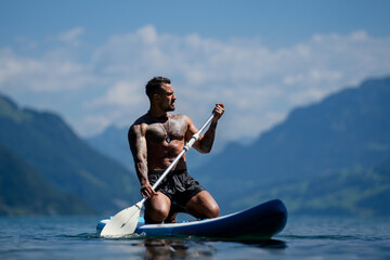 Sexy man with paddle board. Man paddling on paddleboard. Muscular strong Hispanic man on sup board...