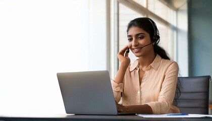 Happy Indian call center agent wearing headset talking to client working in customer support office. Professional contract service telemarketing operator using laptop having conversation. Candid shot