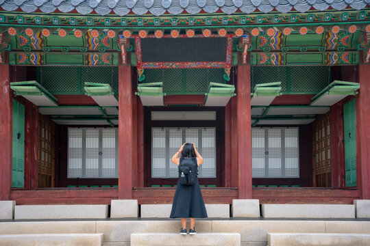 Unrecognizable back view of young Latina woman exploring Korean temple in Gyeongbokgung Palace, South Korea.