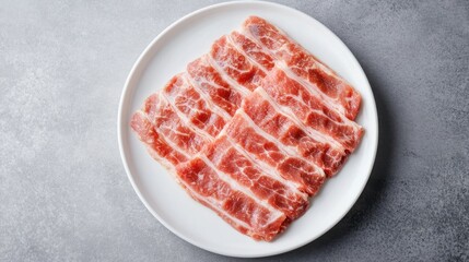 Thinly sliced meat arranged on a plate, ready for cooking or serving.