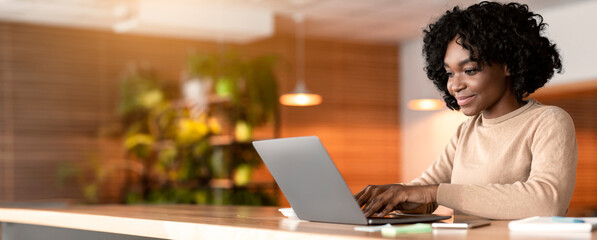 Female blogger black girl working at cafe, typing on laptop, copy space