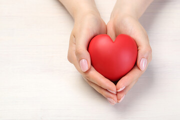 Obraz premium Woman with red decorative heart at white wooden table, closeup. Space for text