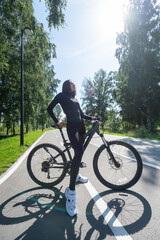 Caucasian woman riding a bike in a park. Vertical photo. 